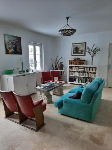 La Grange aux dames في Geville: غرفة معيشة مع أريكة زرقاء وطاولة