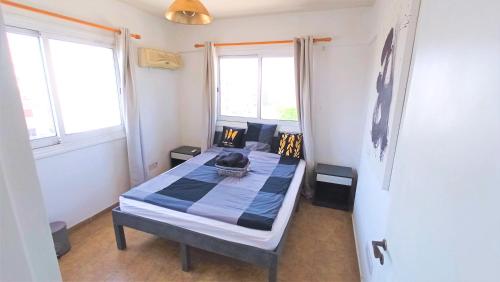 ein Schlafzimmer mit einem Bett in einem Zimmer mit zwei Fenstern in der Unterkunft Luxury Maisonette Apartment -SEA VIEW, NETFLIX, GYM- 5 Min from Beach in Larnaka