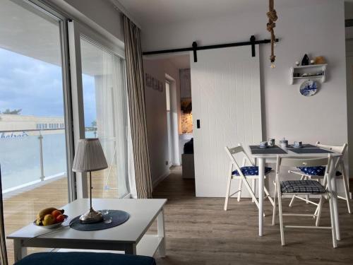 a living room with a table and chairs with a view of the ocean at Apatrament Krewetka in Rowy
