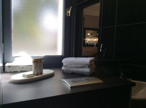 a bathroom with a counter with towels and a mirror at Hotel La Chaumiere in Dole