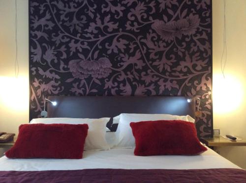 a bedroom with a large bed with red pillows at Hotel La Chaumiere in Dole