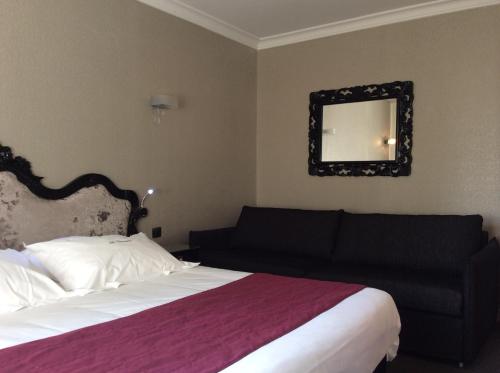 a bedroom with a bed and a couch and a mirror at Hotel La Chaumiere in Dole