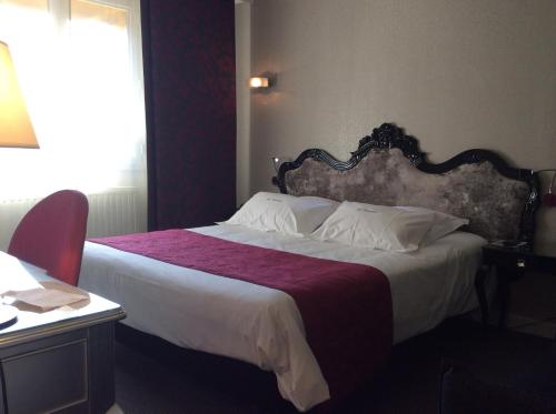 a bedroom with a large bed with a red blanket at Hotel La Chaumiere in Dole