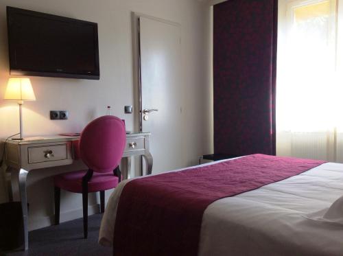 a hotel room with a bed and a desk with a pink chair at Hotel La Chaumiere in Dole