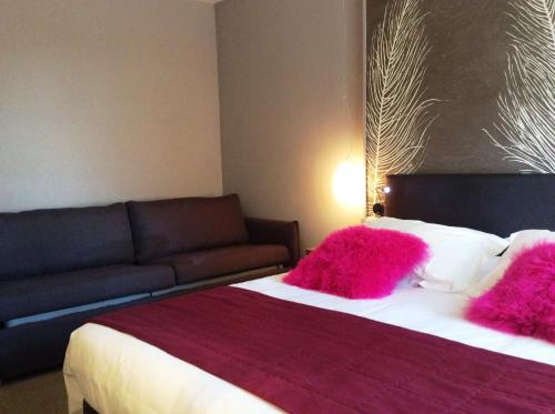 a bedroom with a bed with pink pillows and a couch at Hotel La Chaumiere in Dole