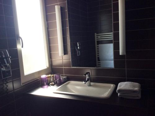 a bathroom sink with a window and a mirror at Hotel La Chaumiere in Dole