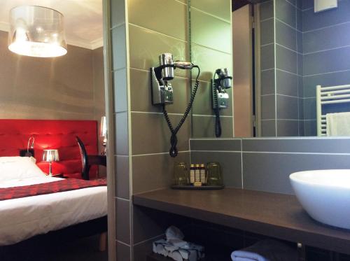 a bathroom with a sink and a mirror at Hotel La Chaumiere in Dole