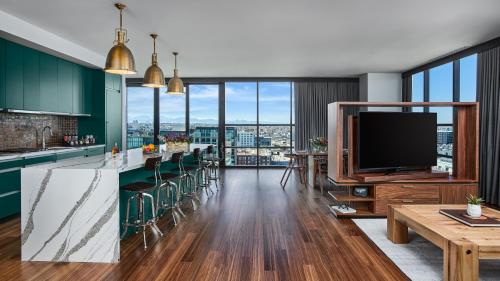 a living room with a tv and a kitchen with green cabinets at The Rally Hotel at McGregor Square in Denver
