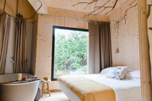 a bedroom with a bed and a large window at The Nest by Cooking and Nature in Alvados