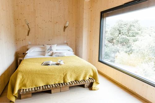 a bedroom with a bed with a yellow blanket and a window at The Nest by Cooking and Nature in Alvados