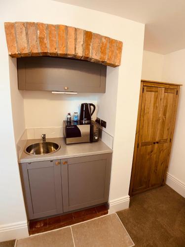 a small kitchen with a sink and a wooden door at Carlton Guest Suites - Weymouth in Weymouth