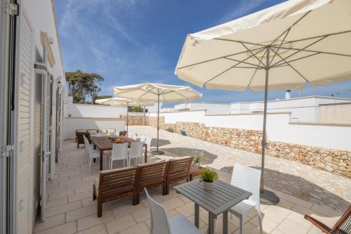 a patio with tables and chairs and umbrellas at B&BLeucaineout in Leuca