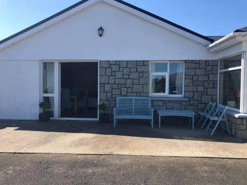 a house with two chairs and a bench on a patio at Luí na Gréine in Gweedore