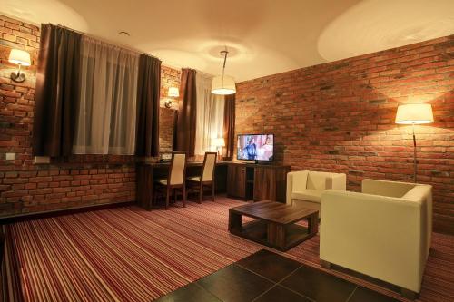 a living room with a brick wall and a table and chairs at Browar CzenstochoviA Hotel&Spa in Częstochowa