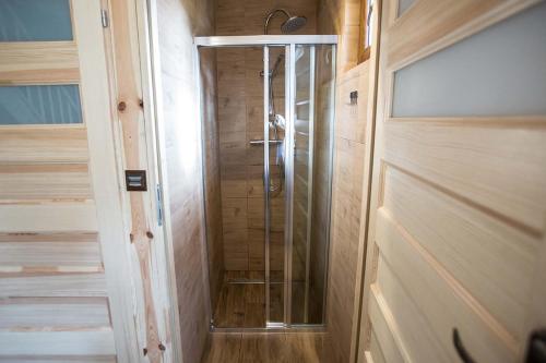 cabina doccia con porta in vetro in bagno di Domki PAGAJ a Zwierzyniec