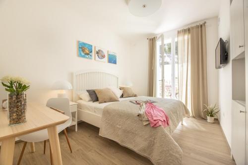 a white bedroom with a bed and a desk at B&BLeucaineout in Leuca
