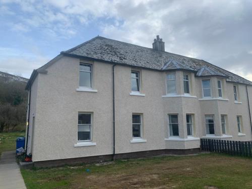 a white house with a black roof at The White City Apartment in Oban