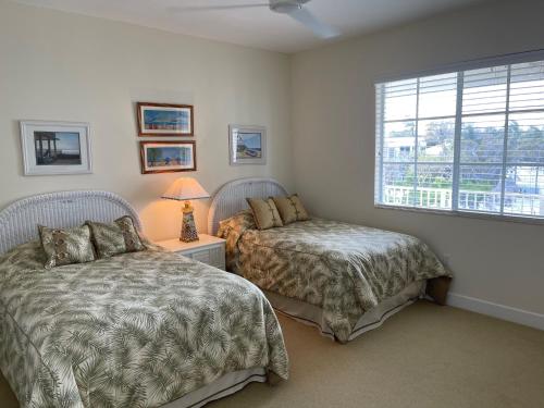 a bedroom with two beds and a window at LICENSED Mgr - LUXURY VIP PENTHOUSE SUITE - OFFERS RESORTS BEST PANORAMIC OCEAN VIEWS! in Key Largo