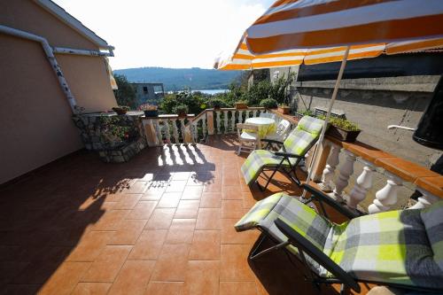 a balcony with lounge chairs and an umbrella and a patio at Apartments Tara - 70 m from beach in Brbinj