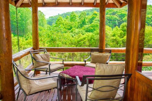 a porch with chairs and a table and a view at Pousada Vinhas do Pinhal in Santo Antônio do Pinhal