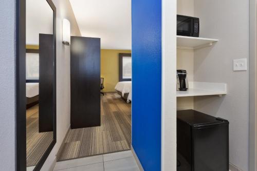 a room with a room with a bed and a mirror at Holiday Inn Express Detroit-Warren/General Motors Technology Center by IHG in Warren