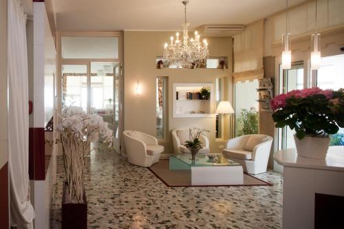 a living room with white chairs and a chandelier at Hotel Canarie in Lido di Jesolo
