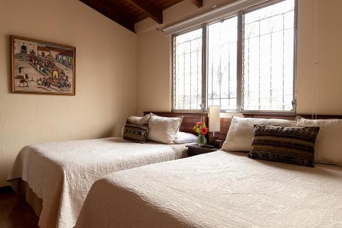 a bedroom with two beds and a window at Hostal Donde Regina in Guatemala