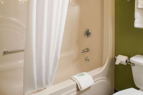a bathroom with a shower with a white shower curtain at Sleep Inn Charleston North in Charleston