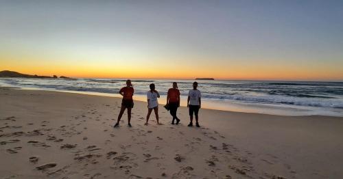 four men standing on the beach at sunset at Vibe House Hostel in Florianópolis