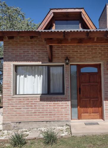 a brick house with a wooden door and a window at Atardecer Serrano in Villa General Belgrano
