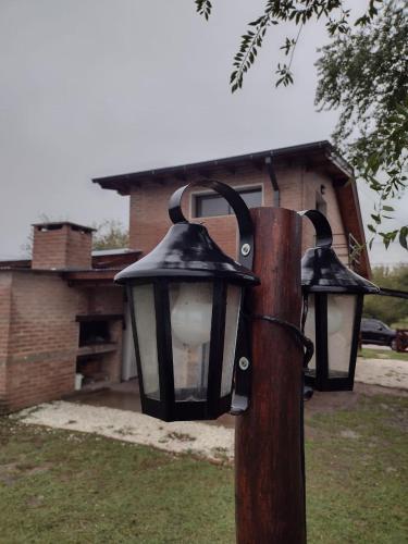 two lights on a wooden pole in a yard at Atardecer Serrano in Villa General Belgrano