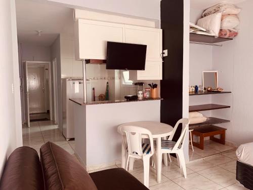 a kitchen and a living room with a table and chairs at Pitangueiras Guarujá Apto com garagem in Guarujá