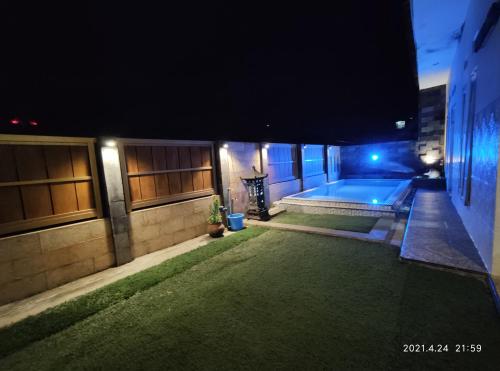 a backyard with a swimming pool at night at Puncak Pinus and Pool in Batu