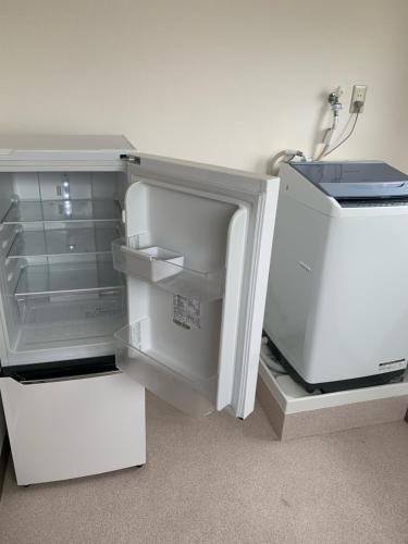 an empty refrigerator with its door open in a room at Hotel Oxio in Okayama