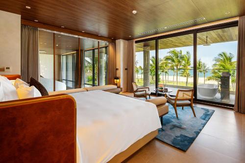 a bedroom with a large bed and a living room at The Five Villas & Resort Quangnam - Danang in Hoi An