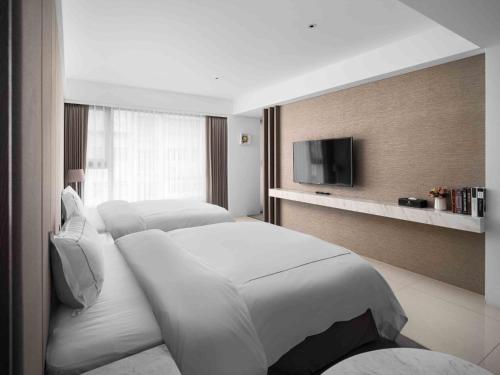 a hotel room with two beds and a flat screen tv at Gamalan Spring Hotel in Jiaoxi