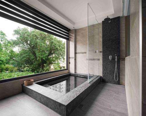 a bathroom with a tub and a shower with a window at Gamalan Spring Hotel in Jiaoxi