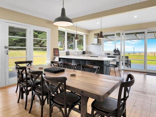 a kitchen and dining room with a wooden table and chairs at Kilcunda Coast House in Woolamai