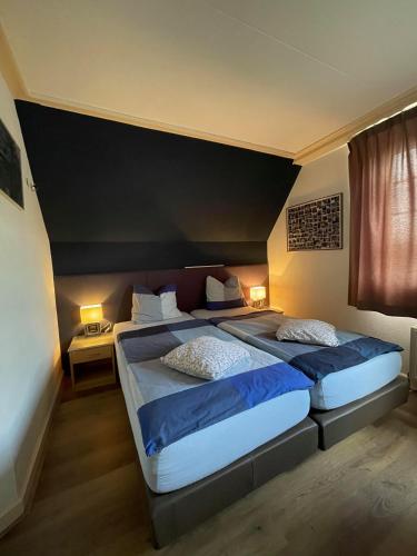 a bedroom with two beds and a black headboard at B&B de Wiekeborg in Oude Pekela