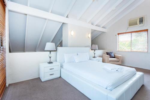 a white bedroom with a white bed and a chair at Como Mezzanine Retreat in Perth