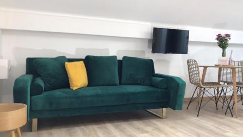 a green couch with a yellow pillow in a living room at Hôtel Eden Cassis - centre-ville- piscine chauffée, jacuzzi et sauna - parking privé in Cassis