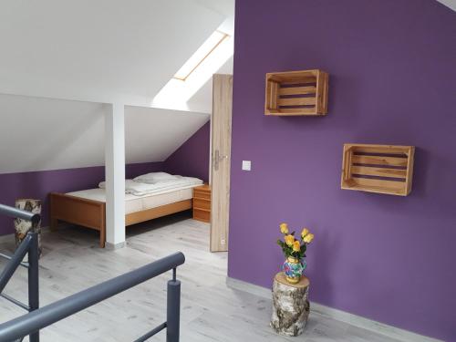 a room with purple walls and a bed and a vase of flowers at Apartamenty Ambra in Dębina