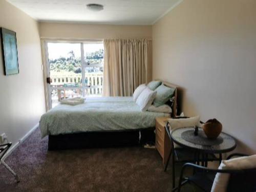 1 dormitorio con cama, mesa y ventana en Breakaway at York Bay, en Days Bay