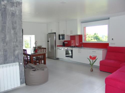 een woonkamer met een rode bank en een keuken bij Quinta de Santa Marinha in Arcos de Valdevez