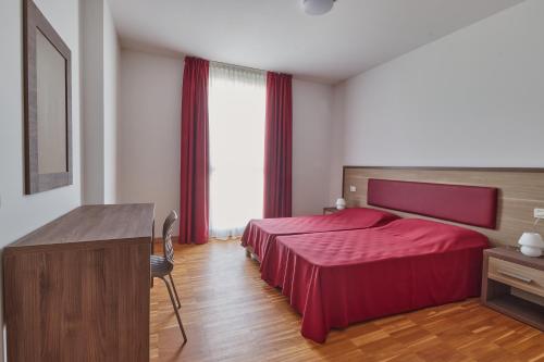 a hotel room with a red bed and a desk at Piazza Lira Schio Residence in Schio