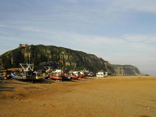 a group of boats sitting on a beach with a mountain at The Cavalier House B&B in Hastings