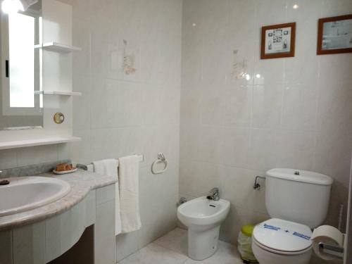 a white bathroom with a toilet and a sink at Apartamento A Canteira in O Grove