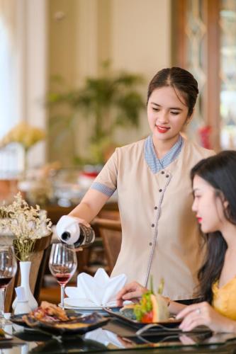 a woman pouring wine into a plate of food at AVS Hotel Phu Quoc in Phu Quoc