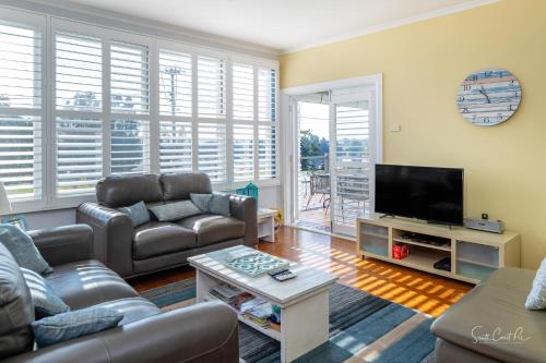 a living room with couches and a flat screen tv at Moruya Holiday House in Moruya