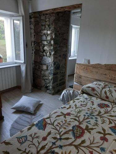 1 dormitorio con cama y pared de piedra en VICINO A ME en Castiglione dʼIntelvi